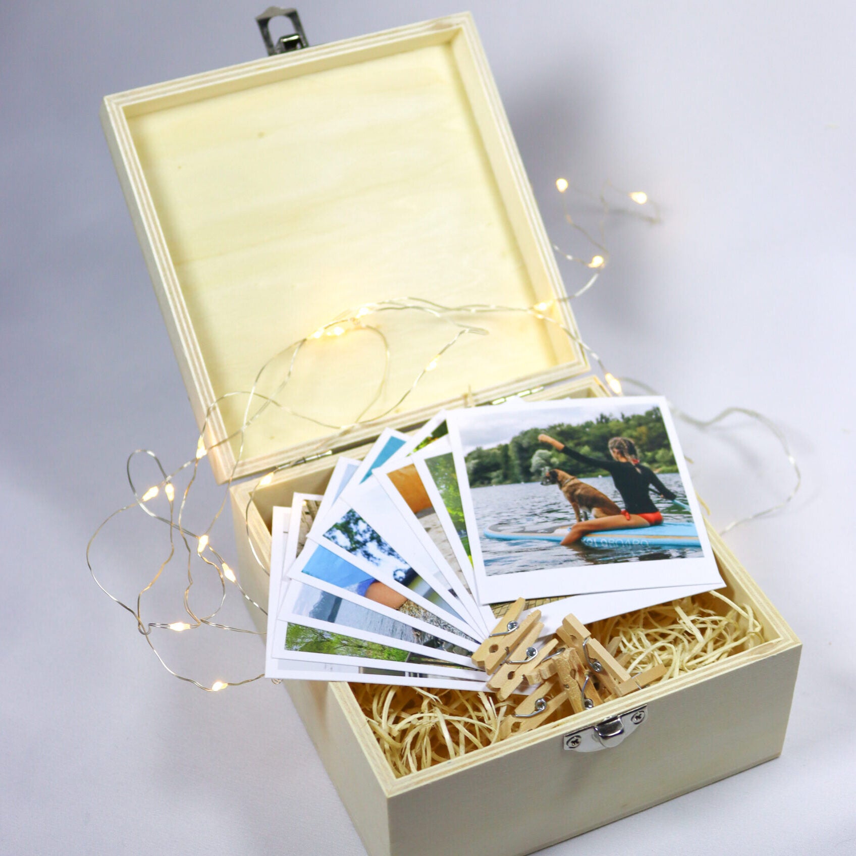 caixa de madeira com polaroids, fio de luz e molinhas